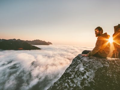 Man relaxing alone on the edge cliff  mountain above clouds travel adventure lifestyle harmony with nature vacations in Norway