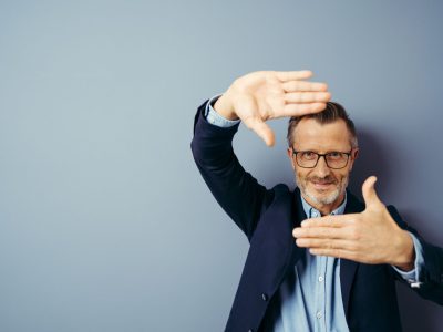 handsome business man over blue isolated background smiling making frame with hands and fingers with happy face. Creativity and photography concept.